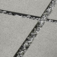 Kostka brukowa i kamień ozdobny - Połączenie jasnoszarych płyt tarasowych z wypełnieniem z białych, ozdobnych kamyków, tworzące nowoczesny i estetyczny wzór.