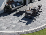 Sklep firmy BrukStone - taras z kostki brukowej w odcieniach szarości z nowoczesnymi meblami wypoczynkowymi, oddzielona od trawnika ozdobnym krawężnikiem.